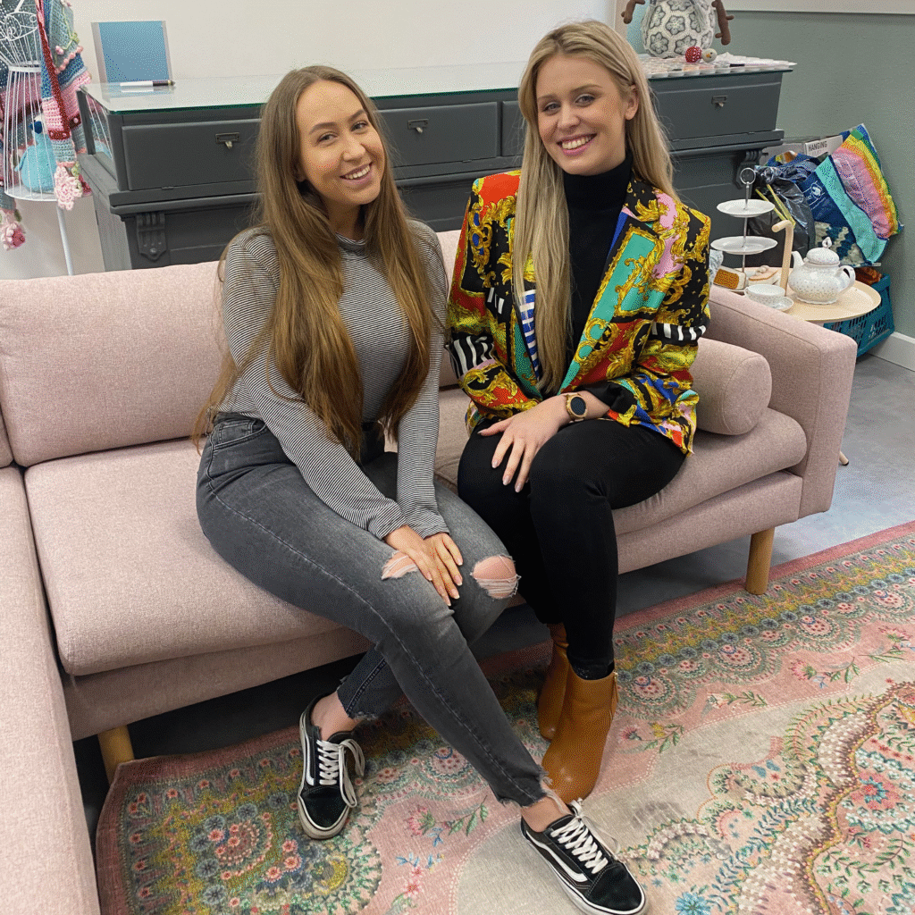 Kaks naist instavad roosa diivani peal.